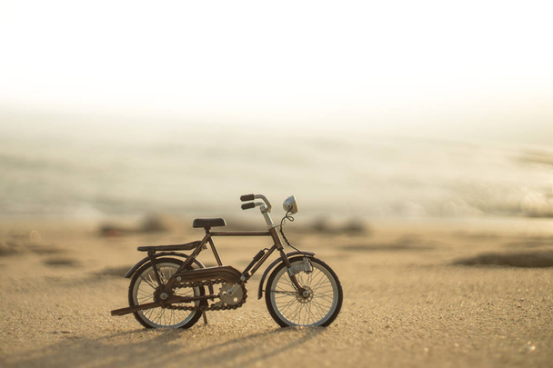 juguete de transporte de bicicletas en la playa de arena del mar en el cielo atardecer
  - Foto, Imagen