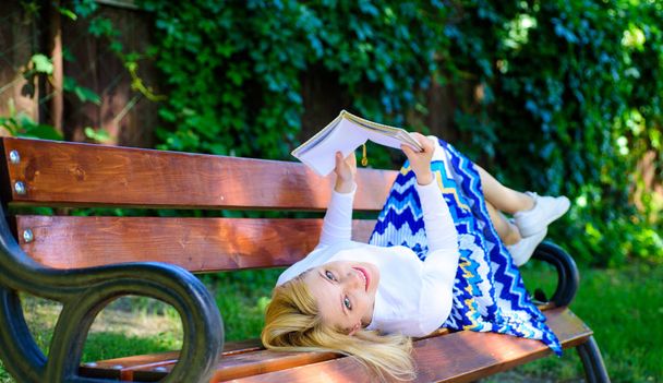 Interesting book. Smart and pretty. Smart lady relaxing. Girl reading outdoors while relaxing on bench. Girl lay bench park relaxing with book, green nature background. Woman spend leisure with book - Photo, Image