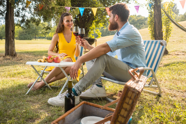 Aşk Romantik piknik sırasında kırmızı şarap ile toasting içinde güzel çift - Fotoğraf, Görsel