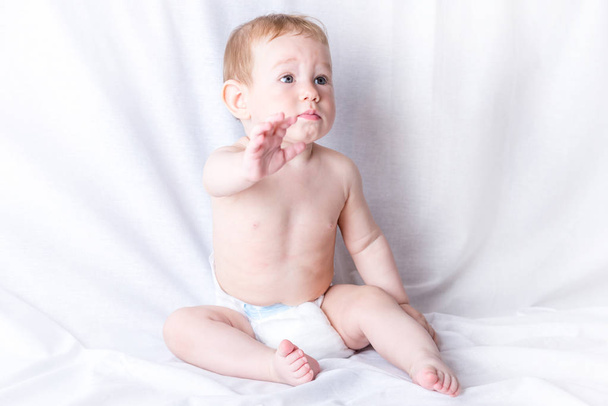 Söpö sinisilmäinen vauva 6-9 kuukautta hymyillen ja leikkien valkoisella taustalla. Lasten tunteita. Puhtaus ja hoito vauvoille
 - Valokuva, kuva