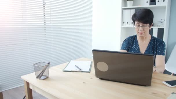 Empresária madura atraente trabalhando no laptop no escritório
 - Filmagem, Vídeo
