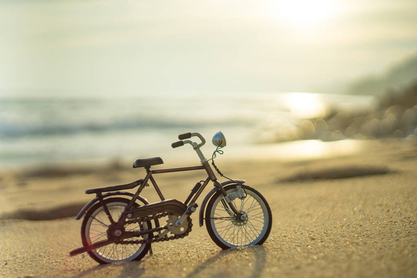 fiets vervoer speelgoed op zand zee strand in de avond avondrood - Foto, afbeelding