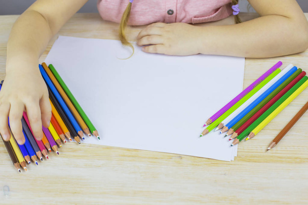 Young girl draws with colored pencils on paper - Foto, afbeelding