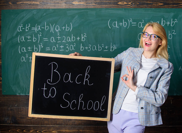 Beginning of new school season. Woman teacher holds blackboard inscription back to school. Are you ready to study. Lady educator in classroom wonders you ready to study. Teacher welcomes school year - Photo, Image