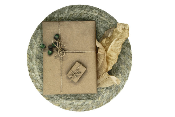 Samenstelling van geschenkdozen verpakt in beige papier en gebundeld met linten. Versierd met jonge eiken eikels en droge bladeren - Foto, afbeelding