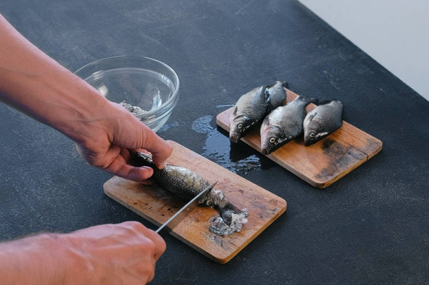 Man cleans carp from the scales. Close-up hands. Cooking a fish. - Foto, Imagen