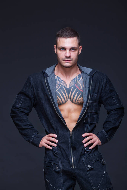 The man with a muscular torso with tattoos on the dark background - Фото, изображение