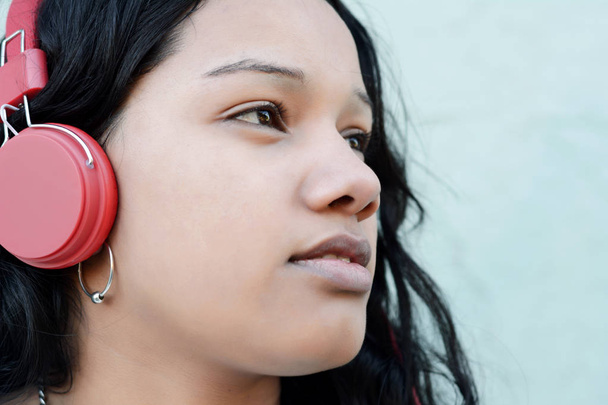 Portrait of young beautiful woman listening to music with red headphones. Outdoors. - Foto, afbeelding