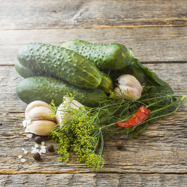 Pickled cucumbers, garlic and spices for pickling in a jar on a wooden table - Fotó, kép