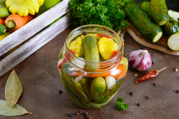 Verduras marinadas em um jarro de vidro. Pepinos variados, pimentas, cenouras, pátios, abobrinha. Pickles.
. - Foto, Imagem