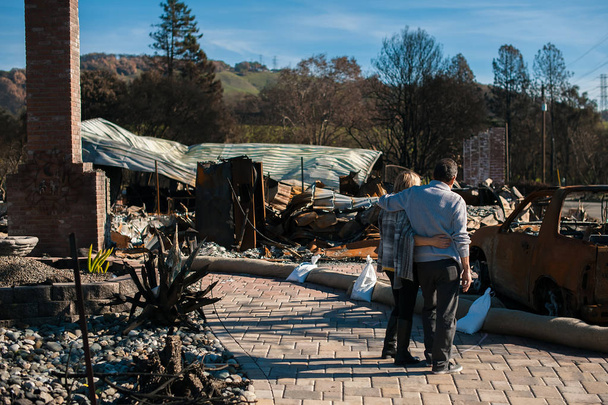 Człowiek i jego żona właścicieli, sprawdzanie spalony i zniszczony ich domu i zagrodzie po pożarze, konsekwencje wypadku klęski ognia. Ruiny po katastrofie pożaru. - Zdjęcie, obraz