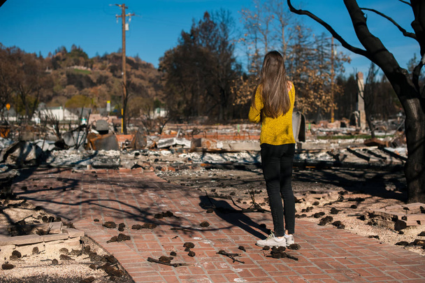 チェックの若きオーナー女性は燃え、火事、火災災害事故の結果の後の家と庭を台無しにしました。火災災害、損失と絶望の概念の後の遺跡. - 写真・画像
