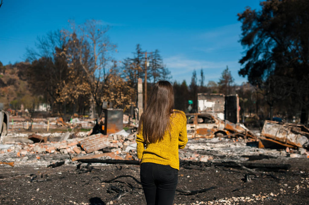 Fiatal tulajdonos asszony ellenőrzése égett, és romos ház és udvar, tűz, tűz katasztrófa baleset következményeinek. Miután tűz katasztrófa, a veszteséget és a kétségbeesés koncepció romok. - Fotó, kép