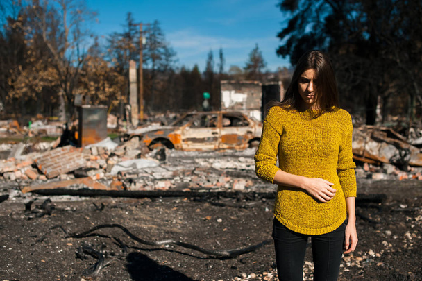 チェックの若きオーナー女性は燃え、火事、火災災害事故の結果の後の家と庭を台無しにしました。火災災害、損失と絶望の概念の後の遺跡. - 写真・画像