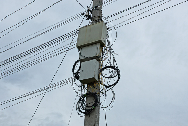 graue Metallkästen an einem Mast mit elektrischen Leitungen - Foto, Bild