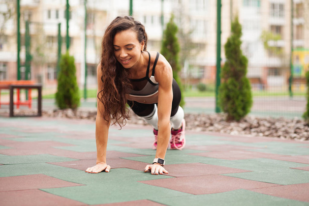 Beautiful sporty woman is working out outdoors - 写真・画像