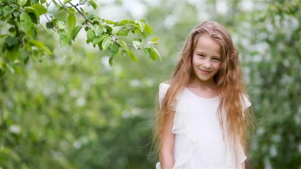 Çiçekli elma bahçesinde küçük sevimli bir kız güzel bir bahar günü - Video, Çekim