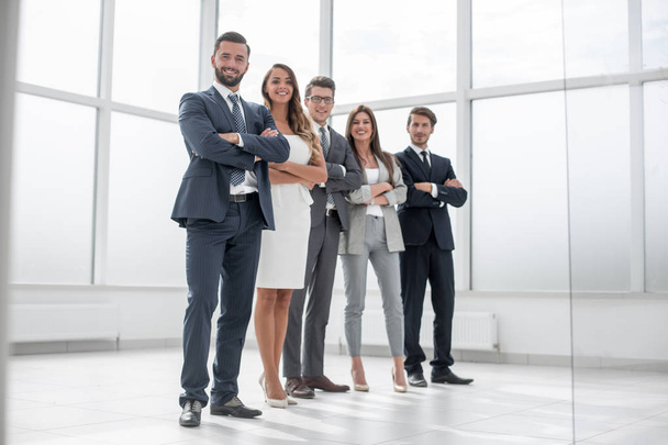 group of businessmen and businesswoman standing in an office with a large window - Фото, изображение