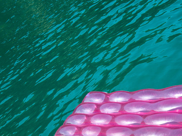 Részlet egy rózsaszín felfújható pad (matrac) víz csepp felületi lebeg, kék, zöld, átlátszó tenger wate - Fotó, kép