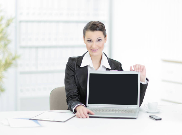 Executive business woman showing a laptop sitting at her Desk - 写真・画像