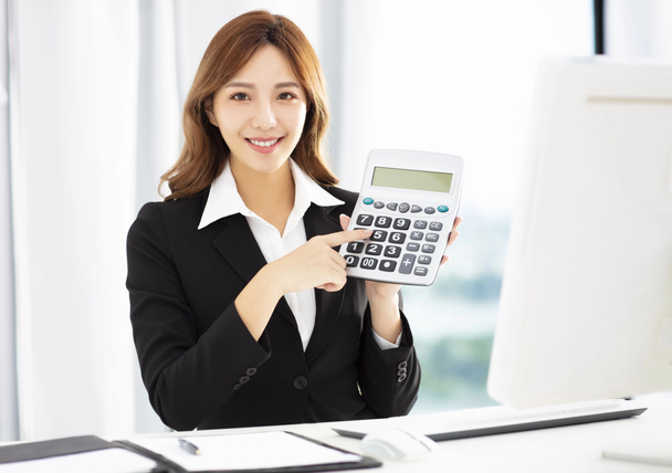 souriante femme d'affaires montrant la calculatrice dans le bureau
 - Photo, image