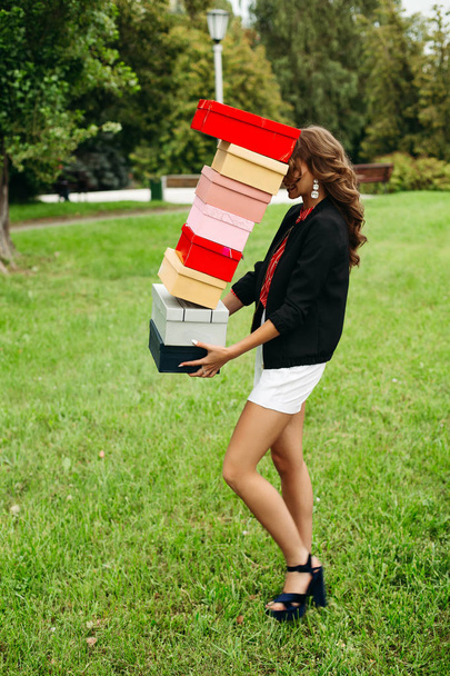 Menina com caixas de sapato caindo enquanto ela caminha no gramado
. - Foto, Imagem