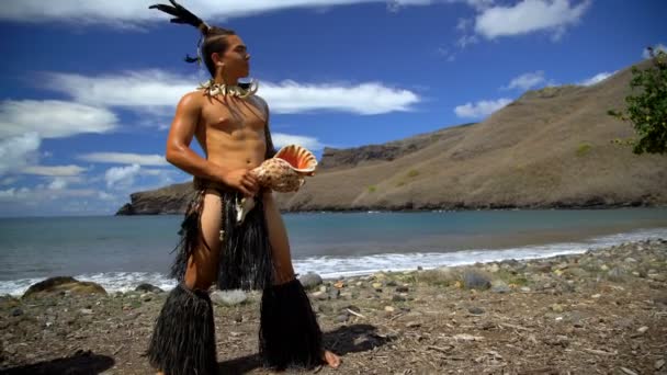 Ansicht der einheimischen Marquesan-Männchen, die am Strand in traditioneller Kleidung auftreten, während sie Muschelschalen-Instrument nuku hiva marquesas Südpazifik spielen - Filmmaterial, Video