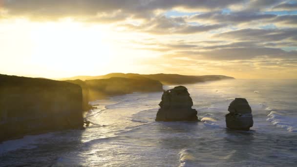 風光明媚な海岸線の石灰岩の崖や岩の周りの海の波の日の出スタック 12 使徒海洋国立公園オーストラリア - 映像、動画