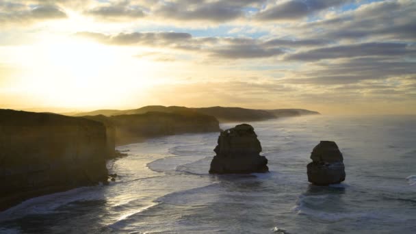 Sunrise door wolken twaalf apostelen Marine Nationaal Park kust met golven van de oceaan rond offshore zee stacks Victoria Australië - Video