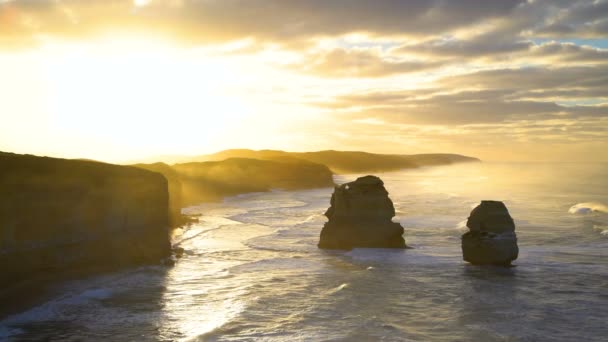 Aamuaurinko yli kalkkikiven kallioita ja valtameren aallot ympärillä offshore rock pinot Kaksitoista apostolien Marine National Park Australia
 - Materiaali, video