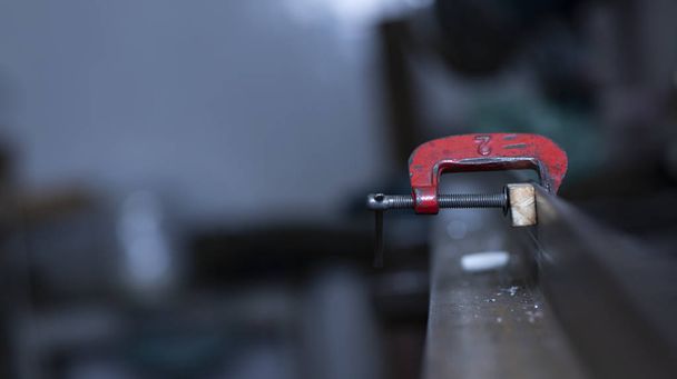 Σφιγκτήρας C σε μια οριζόντια εικόνα να κολλήσει στο σίδηρο και ξύλο, στο χώρο εργασίας  - Φωτογραφία, εικόνα