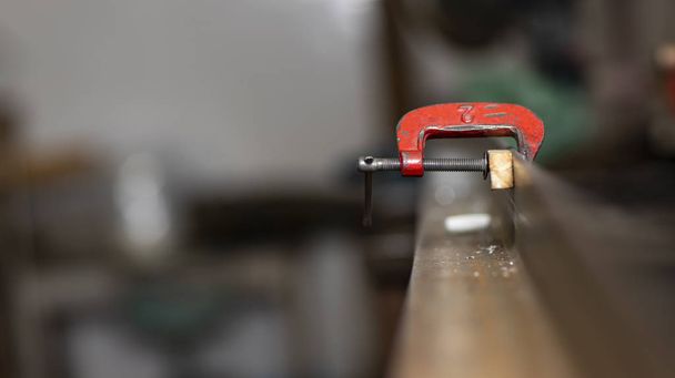 Pinza C in un'immagine orizzontale incollata in ferro e legno, posto di lavoro
  - Foto, immagini