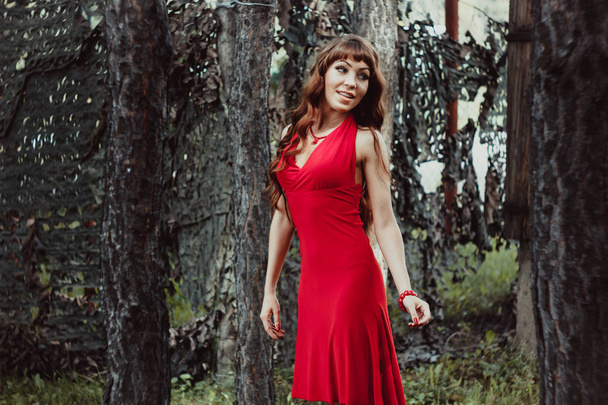 A menina com cabelo ondulado longo em um vestido vermelho na floresta
 - Foto, Imagem