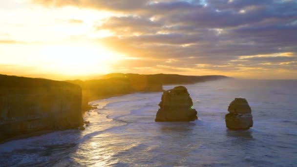 Aamu auringonvalo Kaksitoista apostolien Marine National Park kalkkikiveä kallioita ja offshore rock muodostumat Australian rannikolla aamunkoitteessa
 - Materiaali, video