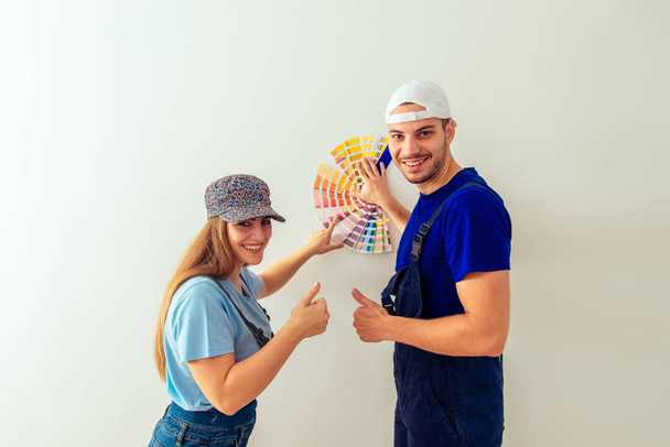 Cute young couple is smiling while holding color guide in living room - Photo, image