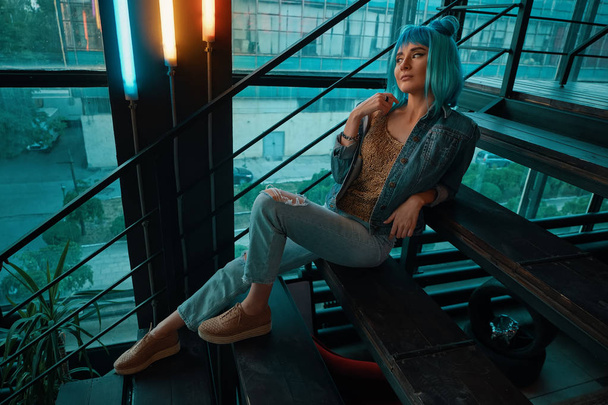  Elegante donna che indossa una parrucca blu seduta sulle scale in un moderno
  - Foto, immagini