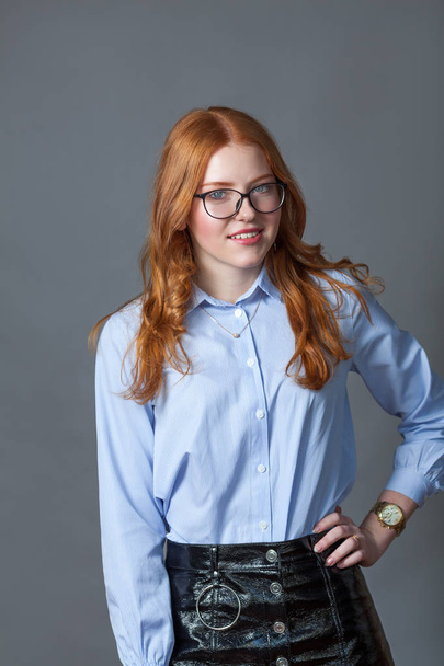 Portrait of happy nice schoolgirl teenager in blue shirt on gray background, studio - Fotografie, Obrázek