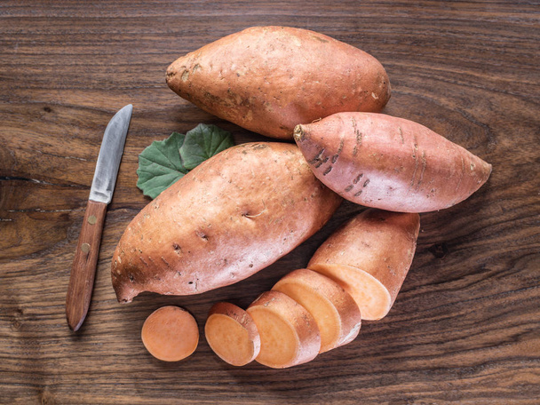 Sweet potatoes on the old wooden table. - Fotografie, Obrázek