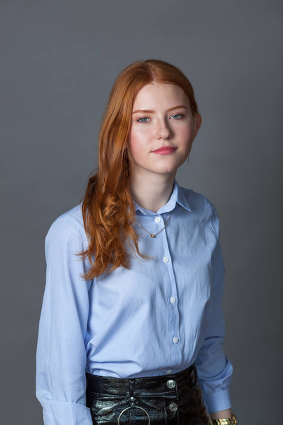 Portrait of happy nice schoolgirl teenager in blue shirt on gray background, studio - Fotoğraf, Görsel