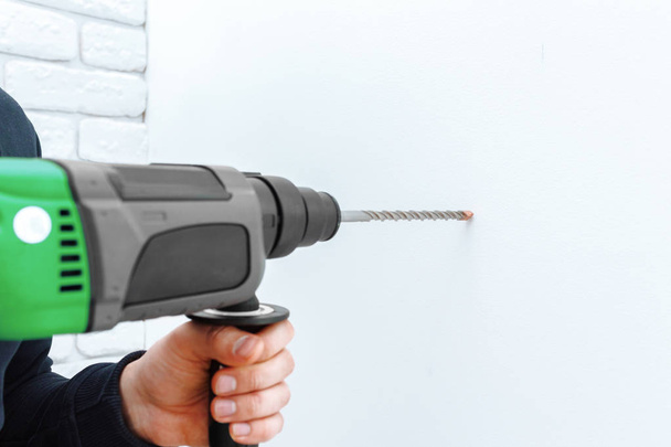 Hands using hammer drill to drill the wall - 写真・画像