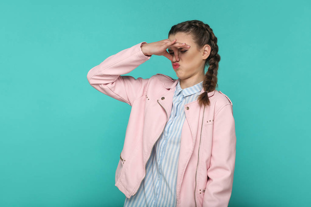 young woman with pigtail hairstyle showing bad smell gesture on blue background - Foto, immagini