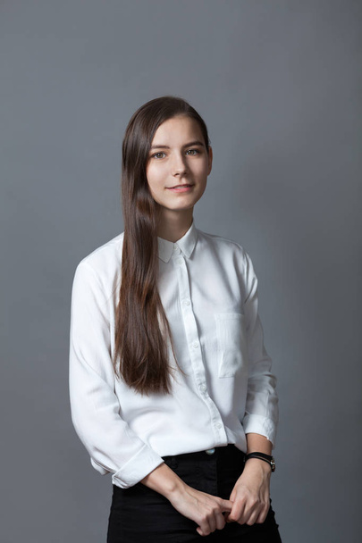 Portrait of happy nice schoolgirl teenager in white shirt on gray background, studio - Foto, imagen