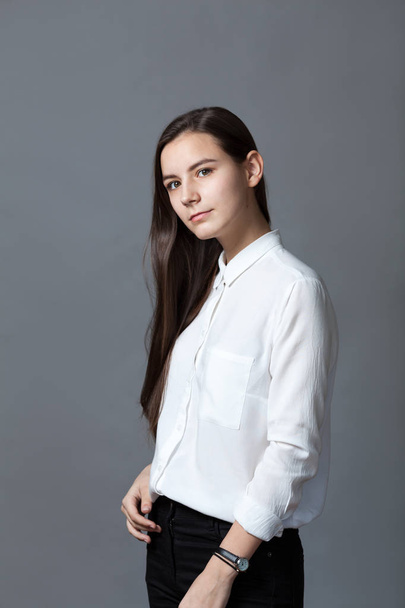 Portrait of happy nice schoolgirl teenager in white shirt on gray background, studio - Foto, Imagem