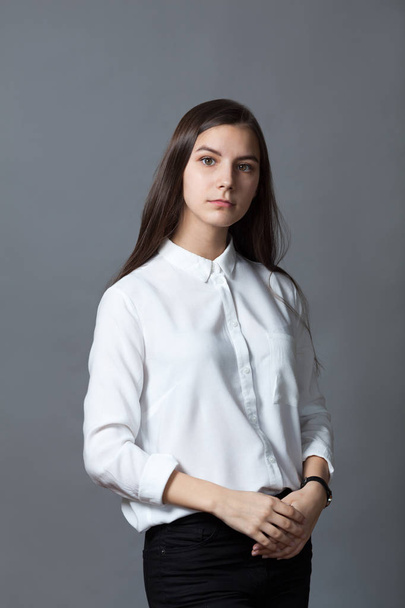 Portrait of happy nice schoolgirl teenager in white shirt on gray background, studio - Фото, изображение
