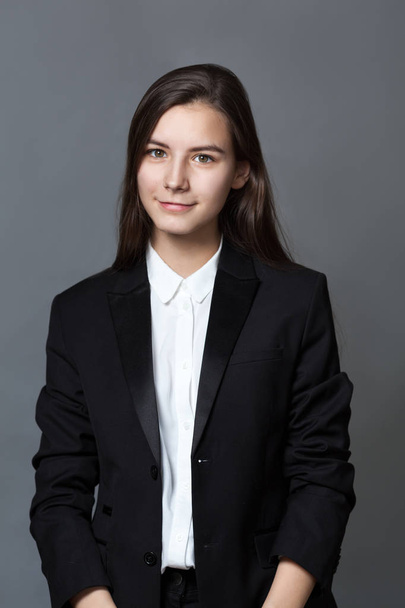 Portrait of happy nice schoolgirl teenager in white shirt on gray background, studio - Fotografie, Obrázek
