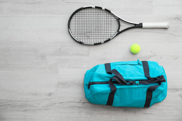 Sports bag, racket and ball on wooden floor, top view - 写真・画像