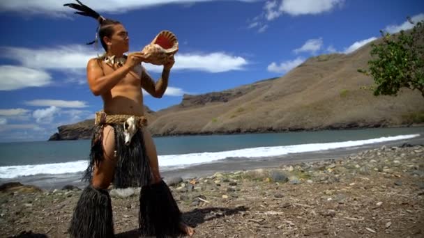 Εγγενής αρσενικό παίζει παραδοσιακά βούκινο κέλυφος μέσο κατά την εκτέλεση στην παραλία φορώντας παραδοσιακή ενδυμασία Νούκου Χίβα Marquesas Νότιο Ειρηνικό - Πλάνα, βίντεο