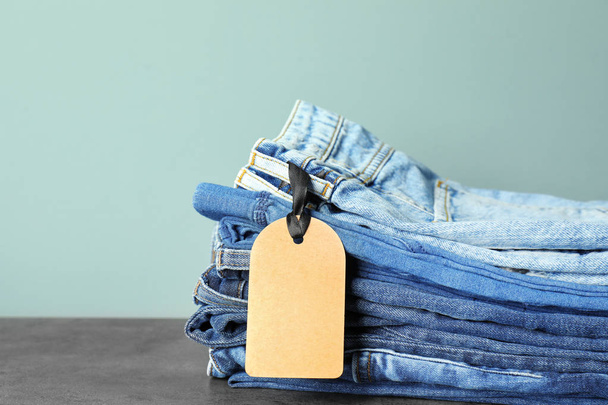 Stack of jeans on table against color background - Foto, Bild