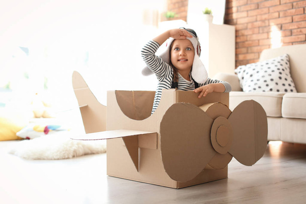 Adorable little child playing with cardboard plane at home - Foto, immagini