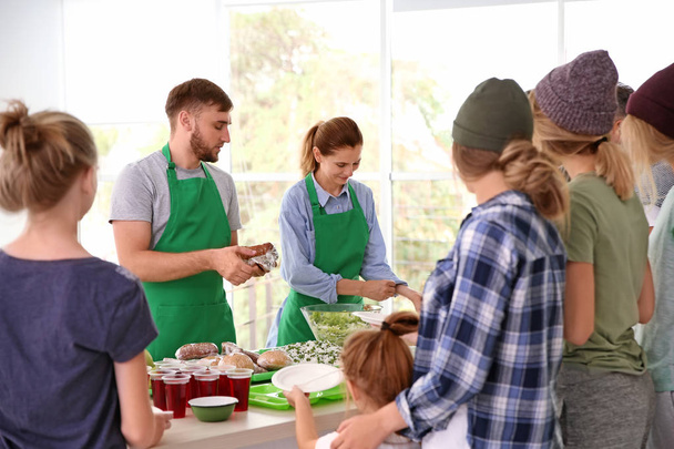 Volunteers serving food for poor people indoors - Fotó, kép